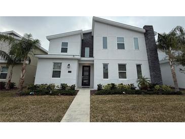 Two-story modern home with gray and white exterior, landscaping, and walkway at 1178 Drop Ln, Kissimmee, FL 34747