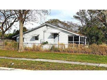White single story house with a screened porch and overgrown yard at 105 N Ortman Dr, Orlando, FL 32805