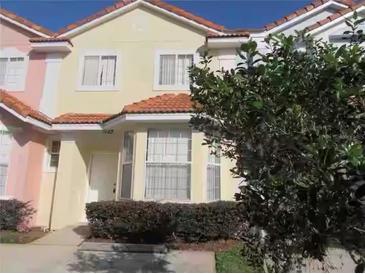 Two-story townhome with light-pink and beige exterior, and a well-manicured front yard at 1128 S Beach Cir, Kissimmee, FL 34746
