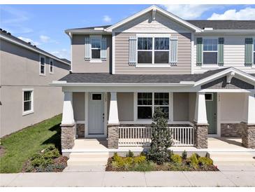Charming two-story townhome featuring a covered front porch with stone accents and manicured landscaping at 1309 Coral Bean Ln, Winter Springs, FL 32708
