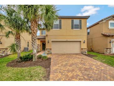 Two-story house with tan siding, brick accents, and a two-car garage at 1505 Mumbai Way, Kissimmee, FL 34747