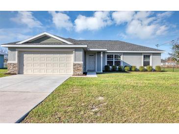 Charming single-story home with a well-manicured lawn and a two-car garage, perfect for a growing Gathering at 21 Juniper Loop Cir, Ocala, FL 34480