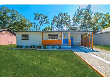 Cute bungalow with modern exterior, landscaped lawn, and a blue front door at 2414 Herbison Dr, Orlando, FL 32810