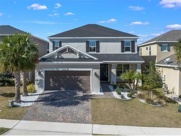 Charming two-story home with landscaped yard, brick driveway and attached two car garage on a sunny day at 2695 Plume Rd, Clermont, FL 34711