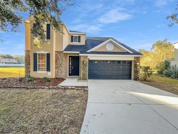 Two-story house with stone accents, a black garage door, and a well-manicured lawn at 3124 Oak Brook Ln, Eustis, FL 32736