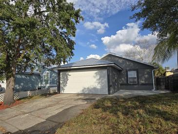 Charming home with a two-car garage, metal roof, and lush green lawn at 1057 Inkberry Ct, Orlando, FL 32811
