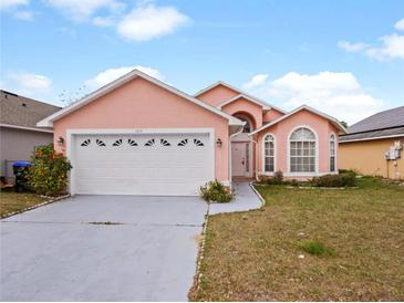 Two-story peach house with a two-car garage and well-maintained lawn at 1614 Stanbury Dr, Orlando, FL 32818