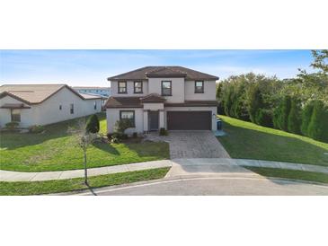 Two-story house with a brown roof, gray siding, and a brick paved driveway at 175 Claffey Ct, Haines City, FL 33844