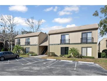 Exterior view of a two-story apartment building with car park, dark trim, and neutral beige siding at 230 Moree Loop # 4, Winter Springs, FL 32708