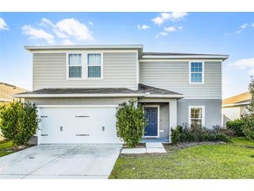 Charming two-story home featuring a blue front door, a two car garage, and manicured lawn at 514 Eagle Landing Blvd, Winter Haven, FL 33880