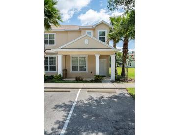 Tan two-story townhome with white columns, landscaping, and parking at 1534 Tranquil Ave, Clermont, FL 34714