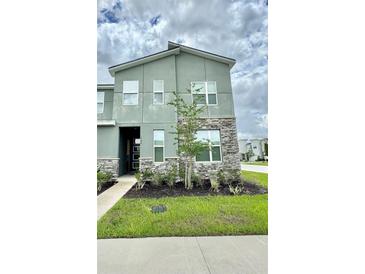 Modern two-story home with stone accents, green facade, and well-maintained landscaping at 1700 Tropical Palms Cir, Kissimmee, FL 34747