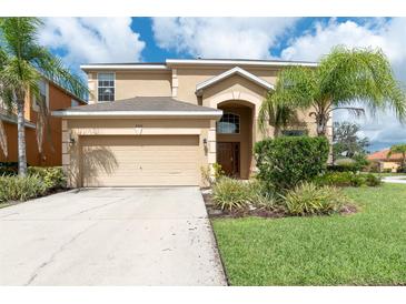 Two-story home featuring a two-car garage, arched entryway, and landscaping at 2553 Dharma Cir, Kissimmee, FL 34746