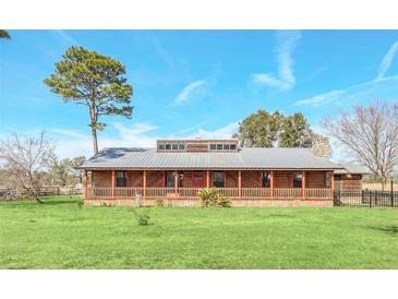 Ranch style home with metal roof, large porch, and fenced yard at 26225 Pitts Rd, Eustis, FL 32736