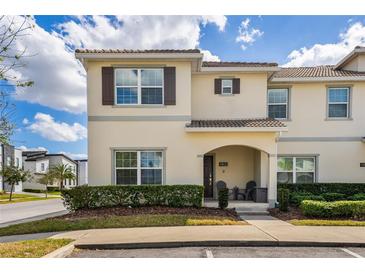 Charming two-story townhouse featuring a well-maintained lawn and covered entryway with neutral colored facade at 4800 Memories Ln, Kissimmee, FL 34746