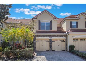 Charming townhome with a red tile roof, stone accents, and two-car garage at 7189 Regina Way, Orlando, FL 32819