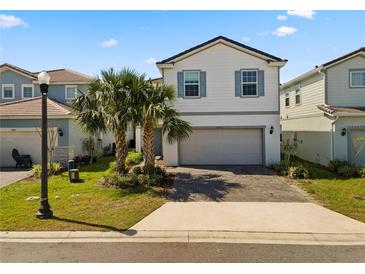 Charming two-story home featuring a two-car garage, well-manicured lawn, and beautiful palm trees at 7343 Oakmoss Loop, Davenport, FL 33837