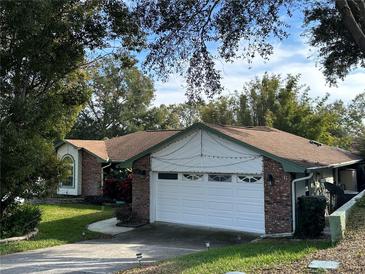 Charming brick home featuring a well-manicured lawn, mature trees, and a two-car garage at 9145 Floribunda Dr, Orlando, FL 32818