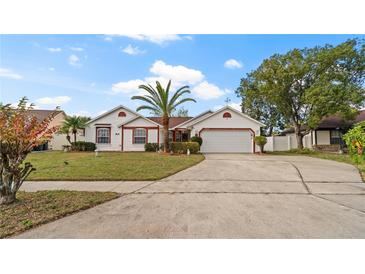 Charming single Gathering home featuring a well-manicured lawn, mature landscaping, and a two-car garage at 9664 Lake Douglas Pl, Orlando, FL 32817