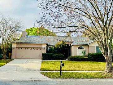 Charming single-story home with a well-manicured lawn, mature tree, and attached two car garage at 14872 Faversham Cir, Orlando, FL 32826