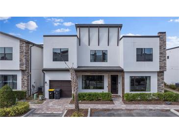 Modern three-story home with attached garage and landscaped front yard at 153 Villa Domani Cir, Davenport, FL 33896