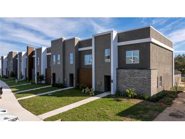 Modern townhome community with gray siding, stone accents, and lush landscaping at 2595 Santorini Dr, Kissimmee, FL 34747