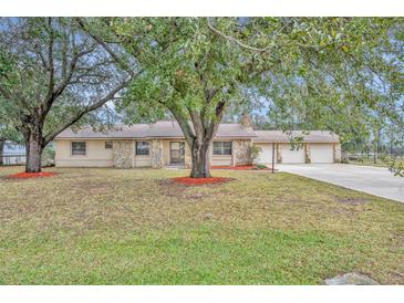 Single-story home with stone accents, mature trees, and a three-car garage at 2770 Windsong Ln, St Cloud, FL 34772