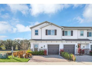 Two-story townhome with gray garage doors and landscaping at 4298 Campsite Loop, Orlando, FL 32824