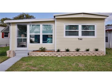 Inviting front exterior with well-kept lawn, small garden, and charming facade, all under a clear blue sky at 662 Sinclair Cir, Tavares, FL 32778
