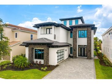 Elegant home featuring stone accents, a driveway and garage, and lush landscaping at 1015 Jack Nicklaus Ct, Kissimmee, FL 34747
