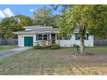 Charming single-story home featuring a ramp, green shutters, and a well-maintained front yard at 1719 Pine Ave, Deland, FL 32724