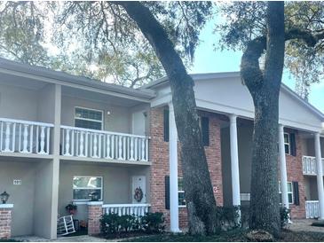Charming condo building featuring brick accents, balconies, and beautiful mature trees at 2500 Lee Rd # 202, Winter Park, FL 32789