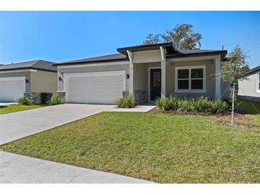 One-story home with a white garage door, landscaped lawn, and a covered entryway at 2896 Lingo Ln, Orlando, FL 32822