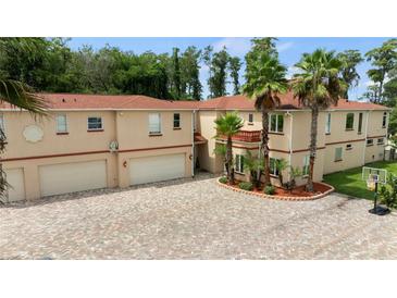 Large, two-story home with an oversized garage and brick paved driveway, surrounded by mature palm trees at 5800 N Dean Rd, Orlando, FL 32817