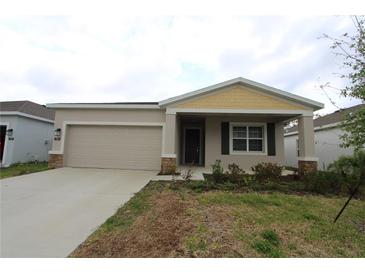 Charming single-story home with a beige exterior, front-facing garage, and a well-maintained lawn at 953 Waterfall Blvd, Davenport, FL 33837