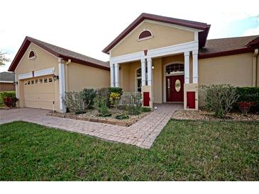 Charming single-story home with a red door, brick walkway, manicured lawn, and two car garage at 1332 Hunterman Lane, Winter Garden, FL 34787
