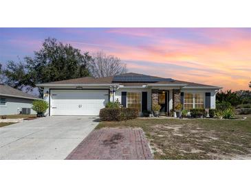 Single-story home with solar panels, attached garage, and landscaped yard at 1523 Whooping Dr, Groveland, FL 34736