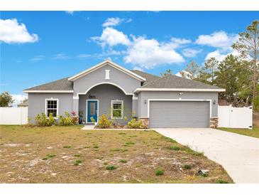 Gray house with a two-car garage and landscaped front yard at 2011 Begonia Way, Poinciana, FL 34759
