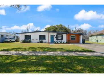 Charming single-story home boasts a well-manicured lawn, inviting blue door, and covered parking at 608 S Oxalis Ave, Orlando, FL 32807