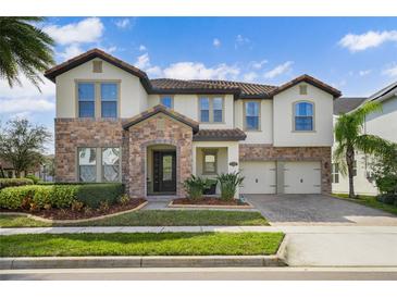 Beautiful two-story home featuring a combination of stone and stucco, a tile roof, and a well-manicured lawn at 13596 Gorgona Isle Dr, Windermere, FL 34786