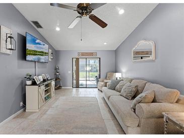 Comfortable living room with neutral walls, tile flooring, and sliding glass doors to the outside at 2214 Se Sawgrass Ct, Winter Haven, FL 33884