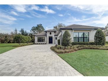 Beautiful home exterior with a brick driveway, manicured landscaping, and a gray tiled roof at 25974 High Hampton Cir, Sorrento, FL 32776