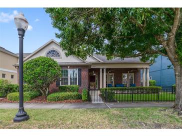Charming red brick home featuring a cozy covered porch and manicured front yard at 3966 Avalon Park West Blvd, Orlando, FL 32828