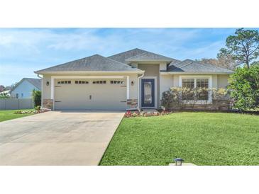 Charming single-story home featuring a well-maintained lawn, a two car garage, and fresh landscaping at 12438 Pine Glen Dr, Leesburg, FL 34788