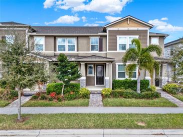 Beautifully landscaped townhome with a manicured lawn, decorative trees, and a welcoming front entrance at 16521 Prairie School Dr, Winter Garden, FL 34787