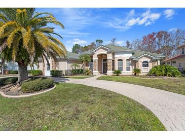 Beautiful single-story home featuring a paved driveway, lush landscaping, and a tile roof at 1941 Southcreek Blvd, Port Orange, FL 32128