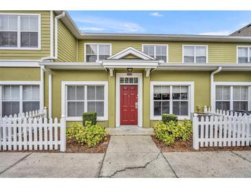 Inviting townhome with charming curb appeal, featuring a red front door and a well-maintained white picket fence at 4004 Santa Maria Dr # 105, Kissimmee, FL 34741