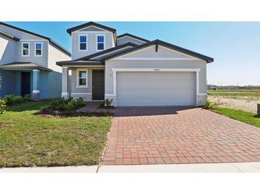 Charming two-story home featuring a gray exterior, a brick driveway, and a well-manicured lawn at 4026 Copperleaf Ln, Poinciana, FL 34759