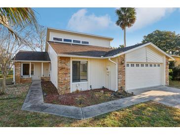 Exterior view of home featuring an attached two-car garage, stone accents, and manicured landscaping at 124 Loon Ct, Daytona Beach, FL 32119