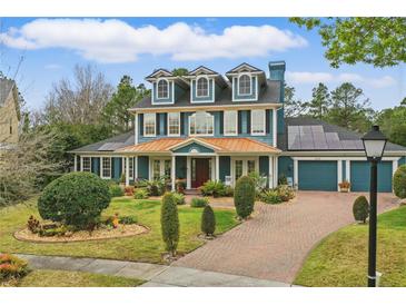 Charming two-story home with a copper roof, lush landscaping, and solar panels at 2438 River Rise Ct, Orlando, FL 32828